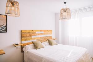 um quarto com uma grande cama branca e 2 almofadas em Duplex Victoria Beach Málaga em Cala del Moral