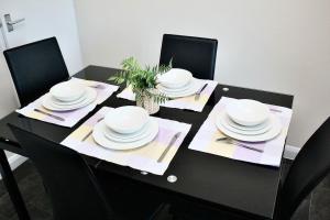 a black table with white plates and utensils on it at Contractor's Haven- 4-Bedroom House with Free Parking, Super Fast WiFi, Fran Properties in Aylesbury, Pets are Welcome! in Buckinghamshire