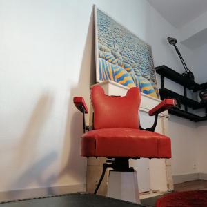 une chaise rouge assise devant un mur dans l'établissement Dormir à la Rochelle 2, à La Rochelle