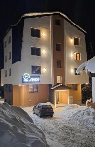 a car parked in front of a building in the snow at Vila Jahor Apartmani JET SET Lux 4,5,6 in Jahorina