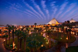 uma vista para as pirâmides e palmeiras à noite em Marriott Mena House, Cairo no Cairo