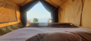 a large bed in a tent with a window at kabwoya Safari camp Kaiso village in Kisaru