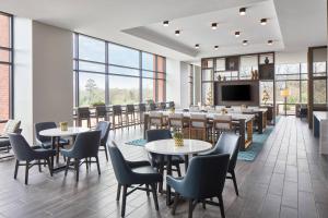 um restaurante com mesas e cadeiras e uma televisão de ecrã plano em UNC Charlotte Marriott Hotel & Conference Center em Charlotte