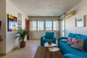 uma sala de estar com um sofá azul e uma mesa em MalagaSuite Carihuela Seaviews em Torremolinos