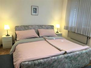 1 cama grande en un dormitorio con 2 lámparas en Schöne, sonnige 25-Zimmer Parterre-Ferienwohnung, en Poschiavo