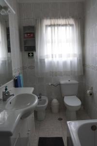 La salle de bains blanche est pourvue d'un lavabo et de toilettes. dans l'établissement Herois Apartment, à Damaia