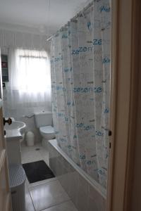 a bathroom with a shower curtain with writing on it at Herois Apartment in Damaia