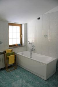 uma banheira branca na casa de banho com uma janela em A. F.antastic V.iew em Costa Volpino