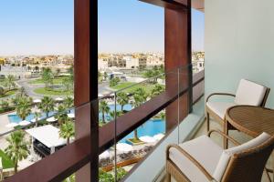 einen Balkon mit Blick auf den Pool und die Palmen in der Unterkunft Marriott Hotel Al Forsan, Abu Dhabi in Abu Dhabi