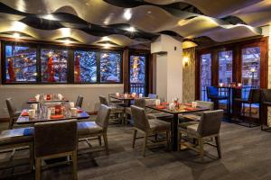 a dining room with tables and chairs and windows at Beaver Creek Lodge, Autograph Collection in Beaver Creek