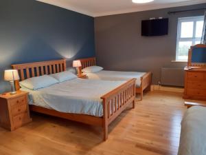a bedroom with two beds and a tv on the wall at Whitethorn Lodge, Bed & Breakfast, Lackafinna in Cong