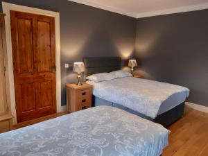 1 dormitorio con 2 camas y puerta de madera en Whitethorn Lodge, Bed & Breakfast, Lackafinna, en Cong