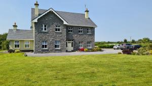 康镇Whitethorn Lodge, Bed & Breakfast, Lackafinna的一座带绿色庭院的大型石屋