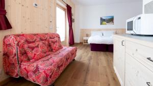 sala de estar con sofá rojo y cama en Italianway - Ripa Fontana 1 Mono, en Valdidentro