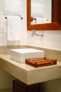 La salle de bains est pourvue d'un lavabo blanc et d'un miroir. dans l'établissement Pousada Praia do Patacho, à Porto de Pedras