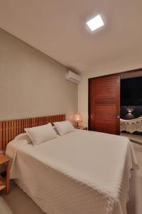 ein Schlafzimmer mit einem großen weißen Bett und einem TV in der Unterkunft Pousada Praia do Patacho in Pôrto de Pedras