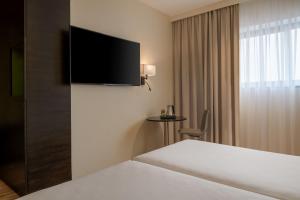a hotel room with a bed and a flat screen tv at AC Hotel by Marriott Milan Sesto in Sesto San Giovanni