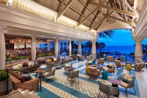 ウィレムスタッドにあるCuraçao Marriott Beach Resortの海を背景にテーブルと椅子が備わるロビー