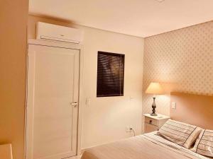 a white bedroom with a bed and a window at Apartamento em foz do Iguaçu in Foz do Iguaçu