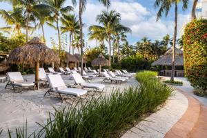 een rij stoelen en parasols op een strand bij The Palms Hotel & Spa in Miami Beach