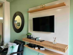 a living room with a television on a wall at Loft em Foz do Iguaçu in Foz do Iguaçu