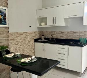 a kitchen with white cabinets and a black counter top at Loft em Foz do Iguaçu in Foz do Iguaçu