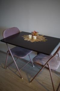 a black table with two chairs and a bowl of flowers at Alanga apartament in Palanga