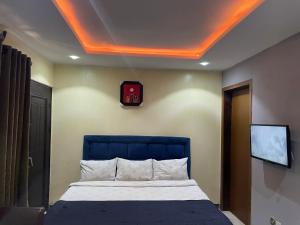 Schlafzimmer mit einem Bett mit blauem Kopfteil und einem TV in der Unterkunft Suite Subzero in Lagos