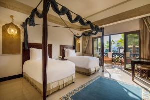 1 dormitorio con 2 camas y balcón en Sharq Village & Spa, a Ritz-Carlton Hotel, en Doha