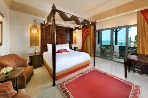 Sharq Village & Spa, a Ritz-Carlton Hotel في الدوحة: غرفة نوم مع سرير وغرفة معيشة