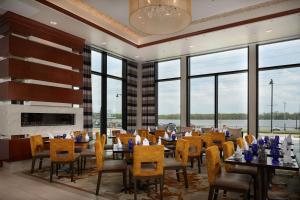 uma sala de jantar com mesas, cadeiras e janelas em The Merrill Hotel & Conference Center, Muscatine, a Tribute Portfolio Hotel em Muscatine
