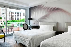 a hotel room with two beds and a balcony at Le Méridien Beach Plaza in Monte Carlo