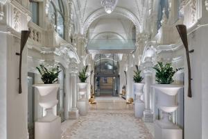 a hallway with white columns and plants in a building at Matild Palace, a Luxury Collection Hotel in Budapest