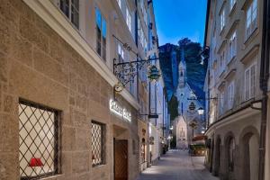 um beco numa cidade com um castelo ao fundo em Hotel Goldener Hirsch, A Luxury Collection Hotel, Salzburg em Salzburgo