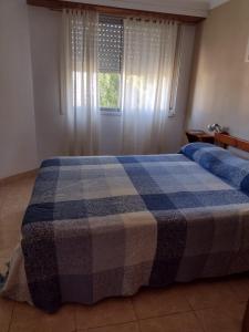 1 dormitorio con 1 cama con manta de cuadros azul en Depto. El duende en Olavarría