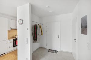een witte keuken met witte kasten en een klok bij Arbio I Ding Design Apartments in Brigittenau Vienna in Wenen