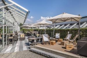 patio z krzesłami, stołami i parasolami w obiekcie Courtyard by Marriott Linz w Linzu