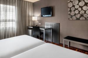 ビトリア・ガステイスにあるB&B HOTEL Vitoria General Álavaのベッド、デスク、テレビが備わるホテルルームです。