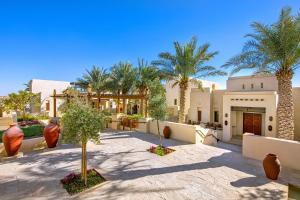 une cour avec des palmiers et un bâtiment dans l'établissement Al Wathba, a Luxury Collection Desert Resort & Spa, Abu Dhabi, à Abu Dhabi