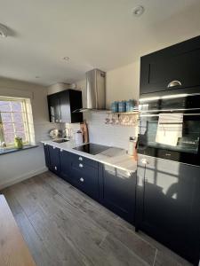 uma cozinha com armários azuis escuros e um forno com placa de fogão em Oystercatcher em Fowey
