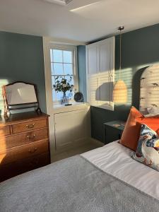 a bedroom with a bed with a dresser and a window at Oystercatcher in Fowey