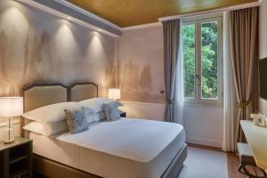 una camera da letto con un grande letto bianco e una finestra di Grotta Giusti Thermal Spa Resort Tuscany, Autograph Collection a Monsummano