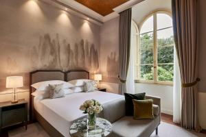 a bedroom with a bed and a vase of flowers on a table at Grotta Giusti Thermal Spa Resort Tuscany, Autograph Collection in Monsummano Terme