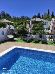 uma piscina num quintal com cadeiras e guarda-sóis em Nicole Luxury Villas em Koskinou