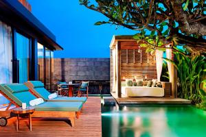 a patio with a pool and chairs and a table at W Bali - Seminyak in Seminyak