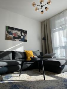 布拉提斯拉瓦的住宿－Sundeck City Centre Apartment，客厅配有一张黑色沙发,设有一张桌子