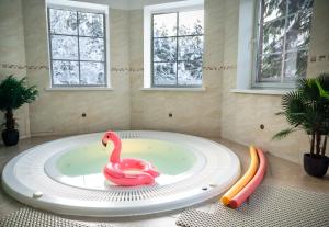 La salle de bains est pourvue d'une baignoire avec un cygne rose. dans l'établissement Agluonenai Park Apartments, à Agluonėnai