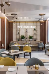 un ristorante con tavoli, sedie e lampadario a braccio di Casa Baglioni Milan - The Leading Hotels of the World a Milano