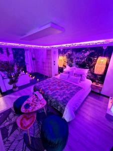 - une chambre avec un grand lit et un éclairage violet dans l'établissement Loveroom Jungle Love Proche Disneyland, à Serris