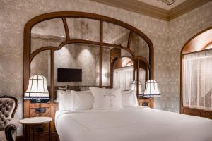 a bedroom with a large white bed and a tv at Palacio Santa Clara, Autograph Collection in Valencia